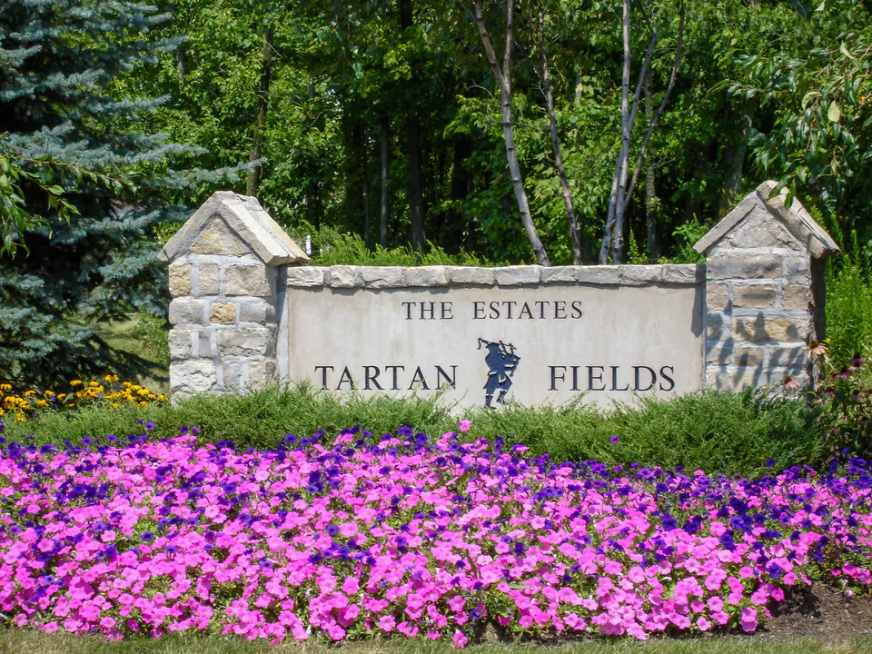 Tartan Fields community entry monument with stone signage, terraced walls, seasonal color, and layered planting